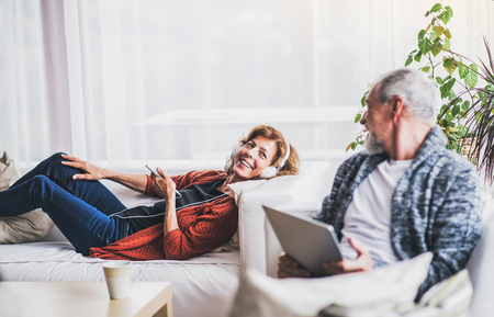 Senior couple with tablet and smartphone relaxing at home.の写真素材