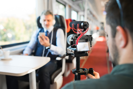 Mature businessman with smartphone travelling by train.の写真素材