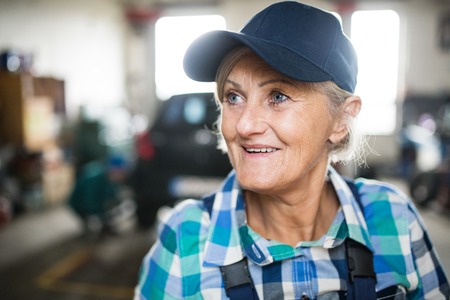 Senior female mechanic repairing a car in a garage.の写真素材