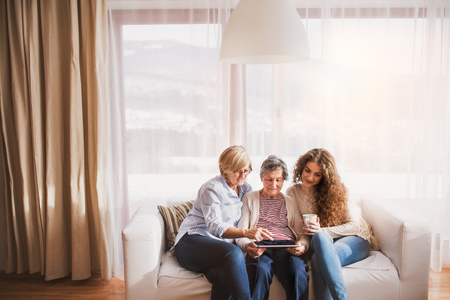 A teenage girl, mother and grandmother with tablet at home.の写真素材