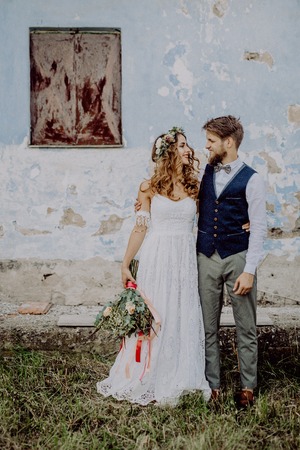 Beautiful bride and groom in front of old shabby house.