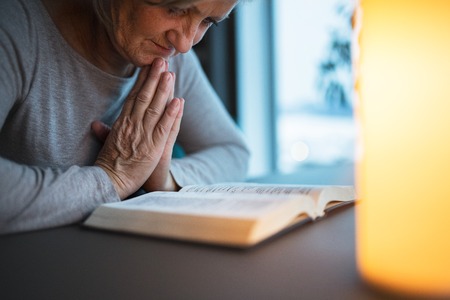 A senior woman praying at home.の写真素材