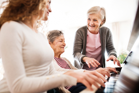 A girl with mother and grandmother playing the piano.の写真素材