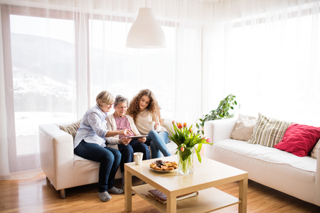 A teenage girl, mother and grandmother with tablet at home.の写真素材