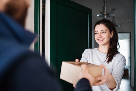 Woman receiving parcel from delivery man at the door.の写真素材