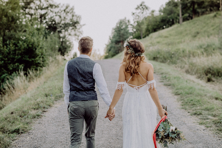 Beautiful bride and groom in green nature, holding hands.の写真素材