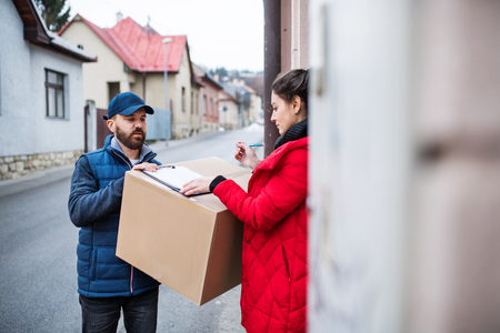 Woman receiving parcel from delivery man at the door.の写真素材
