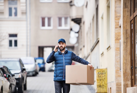 Delivery man with a parcel box on the street.の写真素材
