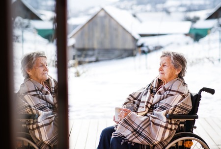 A senior woman outside on a terrace in winter.の写真素材