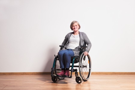 Portrait of a happy senior woman with wheelchair in studio.の写真素材