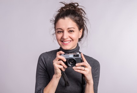 Portrait of a young woman with a camera in studio.の写真素材