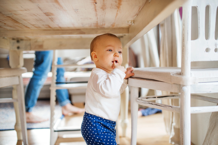 A baby girl under the table at home.の写真素材