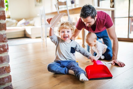 Father and two toddlers with brush and dustpan.の写真素材