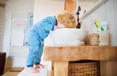 Toddler boy in a dangerous situation in the bathroom.の写真素材