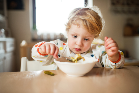 A toddler boy eating at home.の写真素材