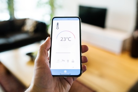 A woman holding a smartphone with smart home screen.の写真素材