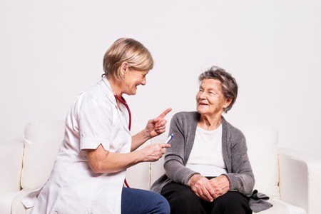 Studio portrait of a senior nurse examining an elderly woman.の写真素材