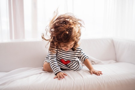 A small happy girl in striped T-shirt at home having fun.の写真素材