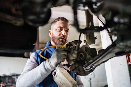 Man mechanic repairing a car in a garage.