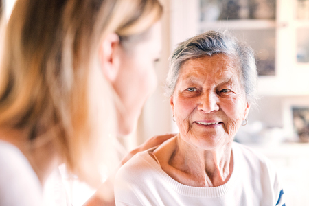 An elderly grandmother with an adult granddaughter at home.の写真素材