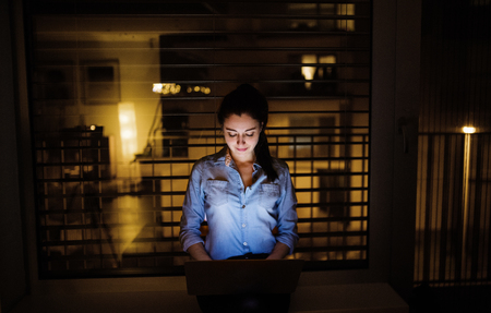 A woman working on a laptop at home or in the office at night.の写真素材