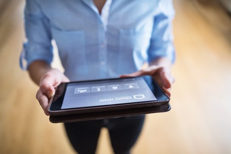 A woman holding a tablet with smart home screen.の写真素材