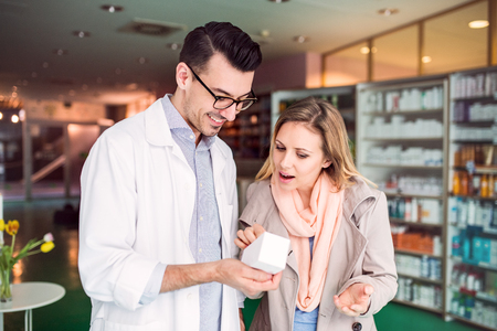 Male pharmacist serving a female customer.の写真素材