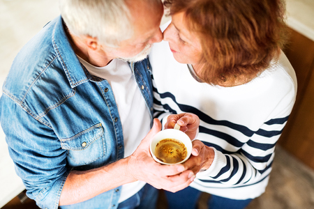 Unrecognizable senior couple holding a cup of coffee at home.の写真素材