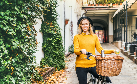 Young woman with bicycle in sunny spring town.の写真素材