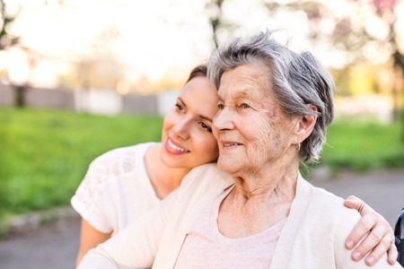 Elderly grandmother and granddaughter hugging in spring nature.