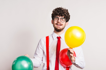 Portrait of a young man with balloons in a studio.の写真素材