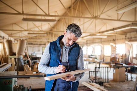 A man worker in the carpentry workshop, working with wood.の写真素材
