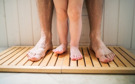 Legs of unrecognizable father and a toddler child in a bathroom at home.の写真素材