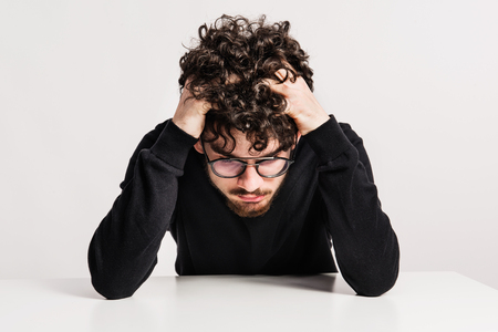 Portrait of an unhappy young man in a studio.