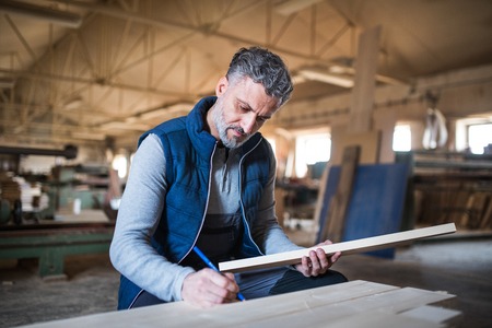 A man worker in the carpentry workshop, working with wood.の写真素材