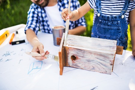 Father with a small daughter outside, making wooden birdhouse.