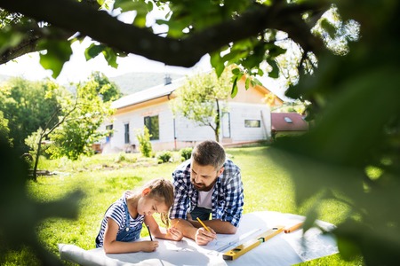 Father with a small daughter outside, planning wooden birdhouse.の写真素材