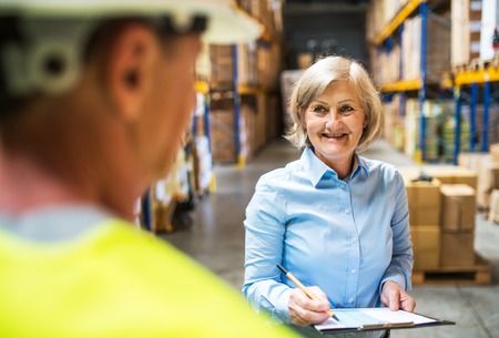 Senior woman manager and man worker working in a warehouse.