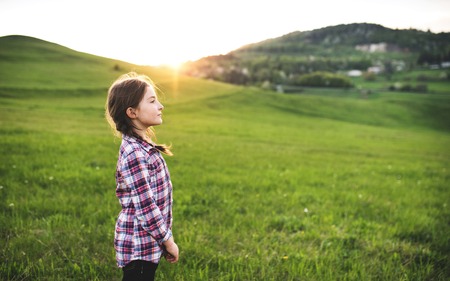 A small girl standing outside in nature.の写真素材