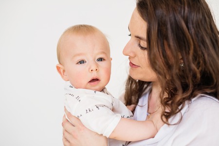 Portrait of a young mother with a baby son at home. Close up.の写真素材