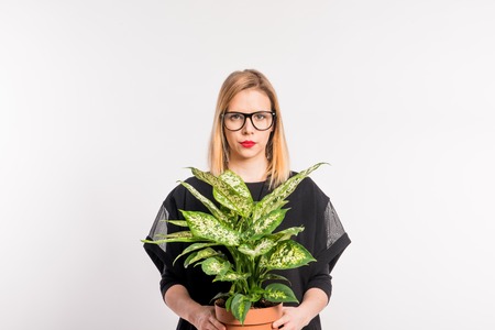 Young beautiful woman with black clothes in studio on white background, holding a plant.の写真素材
