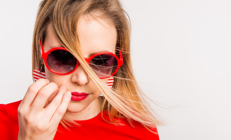 Portrait of a young beautiful woman with red sunglasses in studio.の写真素材