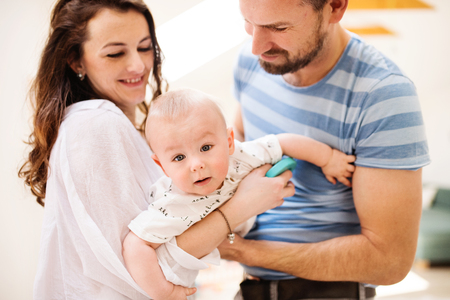 Young family with a baby boy at home, standing and posing for the photo.の写真素材
