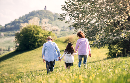 Senior couple with granddaughter outside in spring nature, walking.の写真素材