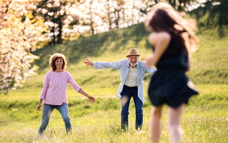 A small girl with grandparents running outside in spring nature.の写真素材