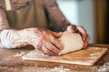 An unrecognizale senior woman kneading dough in the kitchen at home.の写真素材