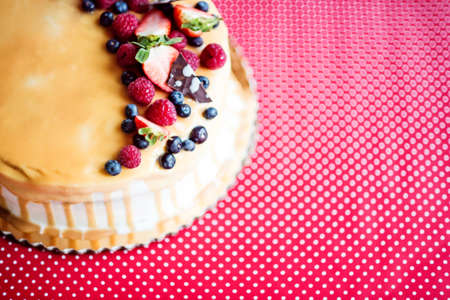 A birthday cake on a glass stand on the table, fruit on top. Top view.の写真素材