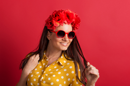 A young woman in studio with sunglasses and red flower headband.の写真素材