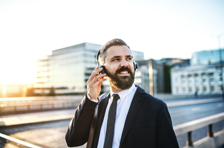 Hipster businessman with headphones in the city, listening to music.の写真素材
