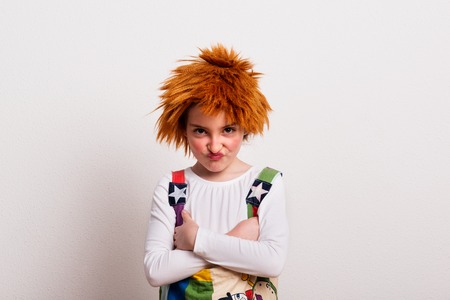 A small girl with a wig and a clown costume in a studio.の写真素材